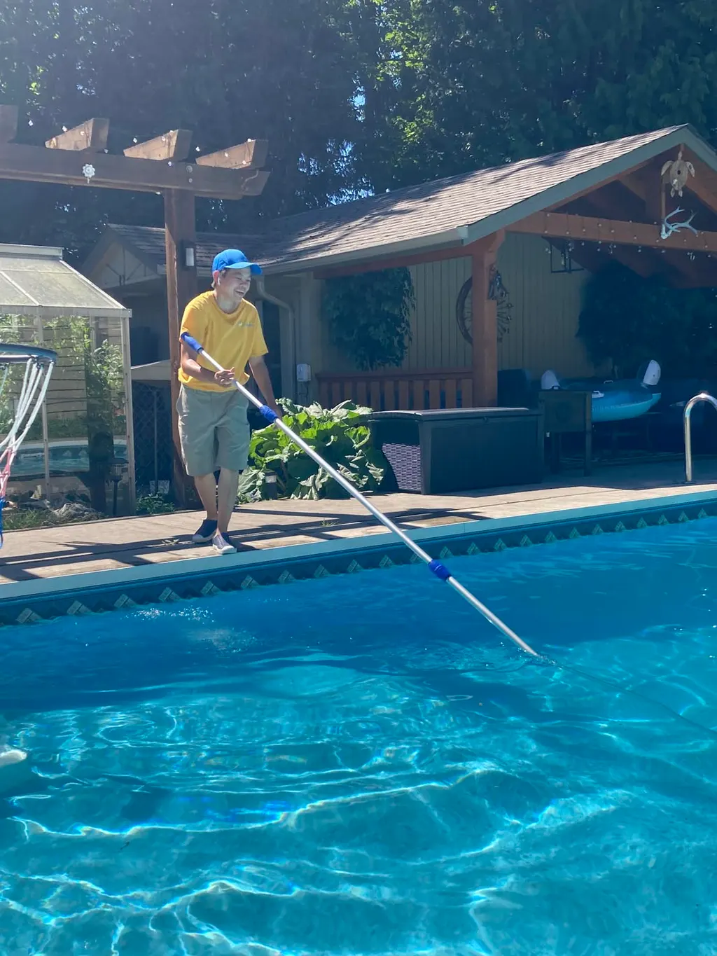 Technician skimming and cleaning a residential swimming pool